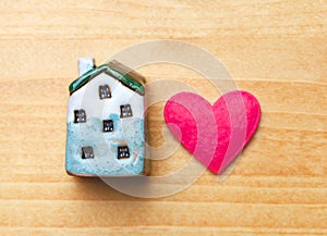 Sweet home concept, mini toy house and red heart on wooden background