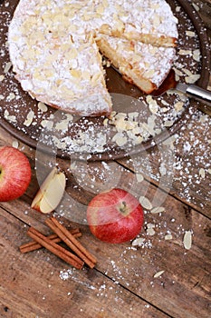 Sweet homemade apple cake with cinnamon and fresh apples on a rustic wooden table