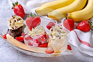Sweet homemade banana split sundae with chocolate vanilla and strawberry ice cream on glass bowl, decorated topping fresh