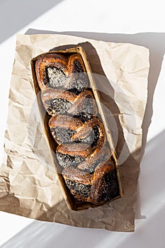 Sweet homemade bread braided with poppy seeds on craft paper