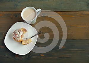 Sweet homemade cinnamon roll on the plate and cup of tea