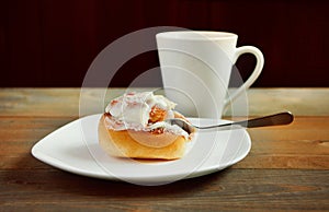 Sweet homemade cinnamon roll on the plate and cup of tea