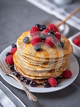 Sweet homemade pancakes with raspberries and blueberries on white plate