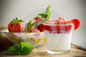 sweet homemade yogurt with strawberry jam and fresh strawberries in a glass cup