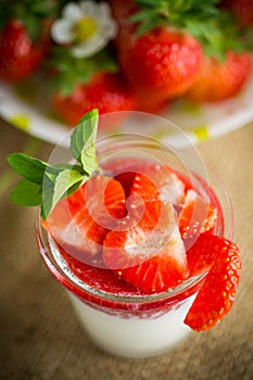 sweet homemade yogurt with strawberry jam and fresh strawberries in a glass cup