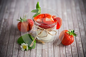 sweet homemade yogurt with strawberry jam and fresh strawberries in a glass cup