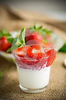 sweet homemade yogurt with strawberry jam and fresh strawberries in a glass cup