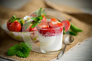 sweet homemade yogurt with strawberry jam and fresh strawberries in a glass cup