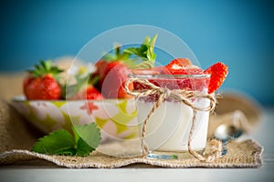 sweet homemade yogurt with strawberry jam and fresh strawberries in a glass cup