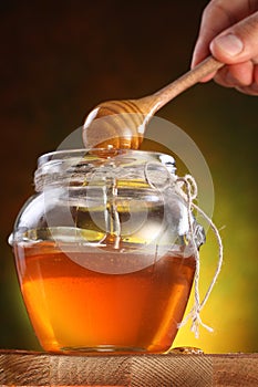 Sweet honey pouring from drizzler into the pot. photo