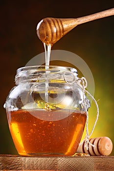 Sweet honey pouring from drizzler into the pot photo