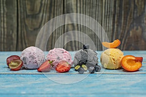 Sweet ice cream in balls on a wooden background. Different berries and fruits