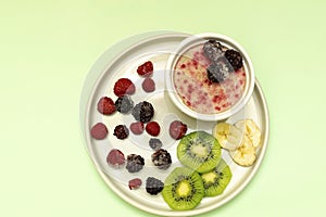 Sweet ice cream yogurt with frozen banana kiwi fruits, blackberry, raspberry berries. Cold fresh summer homemade dessert