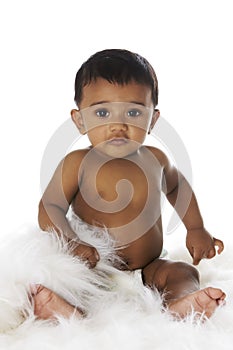 Sweet Indian baby sitting on white fur