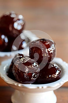 Sweet Jujube or Chinese red date in syrup in white Thai style cup on wood table and space for write wording