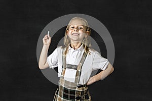 Sweet junior blond schoolgirl smiling happy in front of school classroom blackboard
