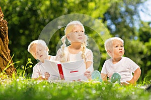 Sweet kids reading an interesting book in the park