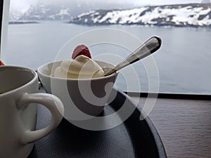 Sweet kiwi jello with cream and a raspberry in a cup onboard a ship with snowy island and sea background