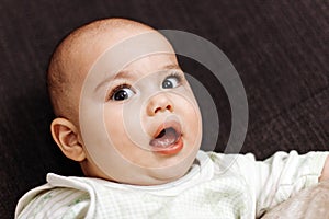 Sweet little baby boy with chubby cheeks and big eyes. Portrait of happy smiling infant