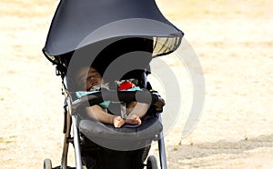 Sweet little baby sleeping in stroller in summer or autumn outdoors