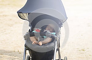 Sweet little baby sleeping in stroller in summer or autumn outdoors