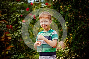 Sweet little boy drinking mineral water from the plastic bottle,