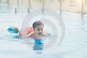Sweet little boy, swimming in big swimming pool, summertime