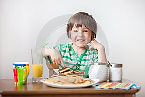 Sweet little caucasian boy, eating pancakes