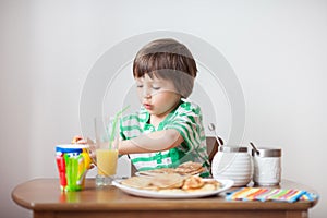 Sweet little caucasian boy, eating pancakes