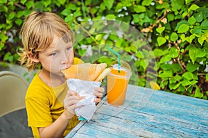 Sweet little caucasian boy, eating pancakes and drinking orange juice