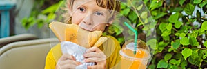 Sweet little caucasian boy, eating pancakes and drinking orange juice BANNER, LONG FORMAT