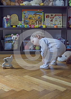 Sweet little child boy having fun at home playing with colorful toys, on the floor. Indoor activity for kids