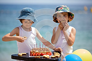 Sweet little children, twin boys, celebrating their sixth birthday on the beach