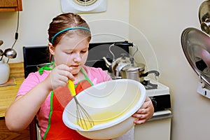 Sweet little cute girl is learning how to make a cake, in the home kitchenlearns to cook a meal in the kitchen