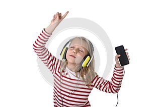 Sweet little girl with blonde hair listening to music with headphones and mobile phone singing and dancing happy