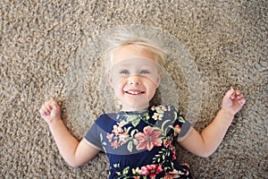 Sweet Little Girl Child in Flower Dress Laying on Carpet, Smilin