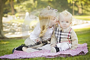 Sweet Little Girl Kisses Her Baby Brother at the Park