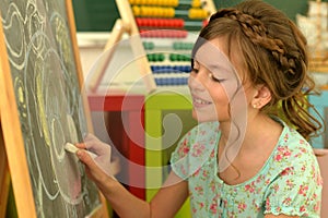 Sweet little girl learning happily in front of her blackboard