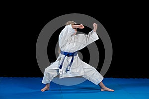 Sweet little girl in martial arts practice like karate kid alone isolated on black background