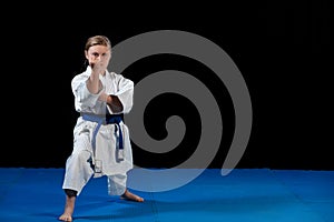 Sweet little girl in martial arts practice like karate kid alone isolated on black background