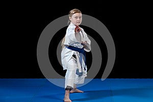 Sweet little girl in martial arts practice like karate kid alone isolated on black background