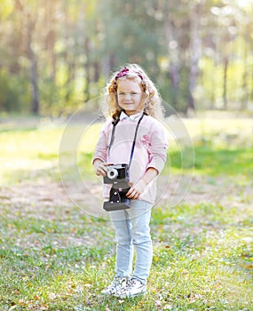 Sweet little girl with old vintage retro camera outdoors
