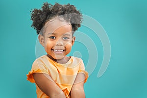 Sweet little girl outdoors with curly hair smiling on blue background