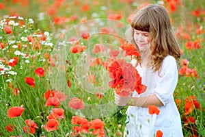 Sweet little girl pick a flowers in a wild meadow with poppies a