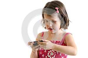 Sweet little girl in pink dress play on smartphone concetrated i