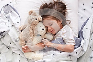 Sweet little girl sleeping with toys in crib. Close up portrait of infant sleeping in cot. Beautiful toddler sleeping with toy