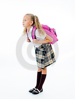 Sweet little girl in uniform carrying heavy big pink backpack or school bag full causing stress and pain on back due to overweight