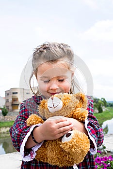 Sweet little holding teddy bear in her arms