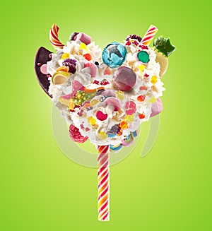 Sweet Lolipop in Heart form of whipped cream with sweets, jellies, heart front view. Crazy freakshake food trend. Front photo