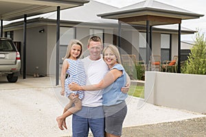 Sweet loving family portrait with husband and wife holding beautiful little daughter posing together in front of modern house